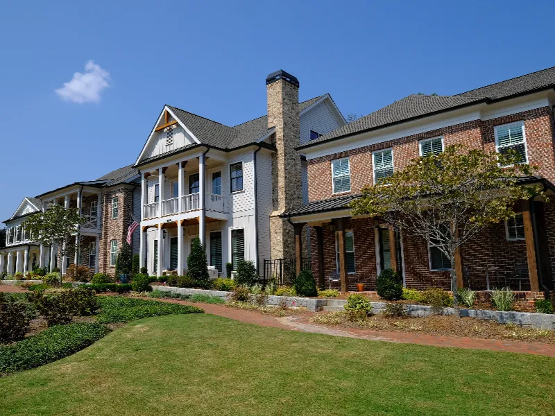 Row of modern townhouses with brick and siding exteriors under a clear blue sky.