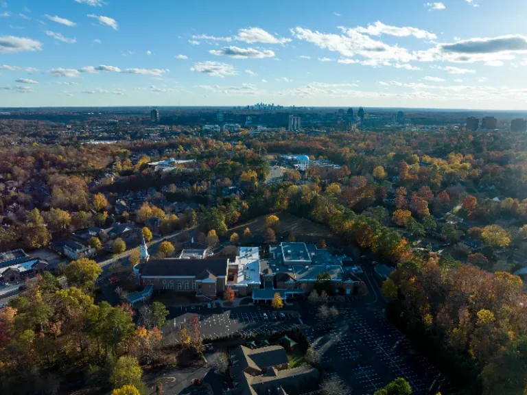 Aerial view of a suburban area with autumn trees and a church with a steeple in the foreground.