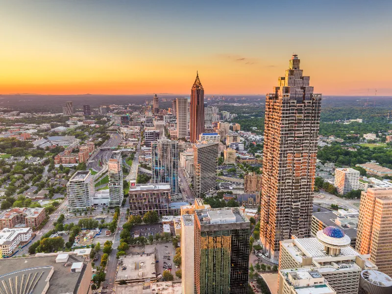 Downtown city skyline at sunset with tall buildings and a clear sky.