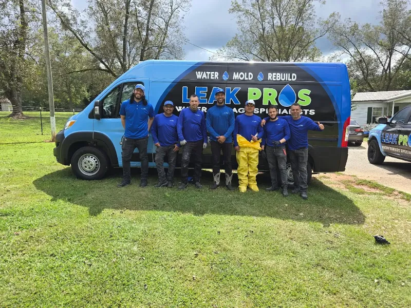 Seven workers in blue shirts stand in front of a blue van with "Leak Pros" branding on the side.
